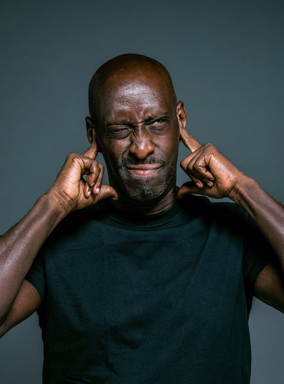 man in black top covering ears with fingers